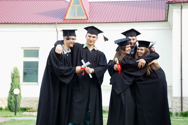 I laureati con diplomi in mano si abbracciano felicemente
 - Foto, immagini