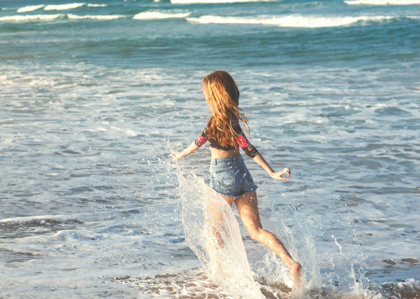 girl walking on the sea at sunset - Фото, зображення