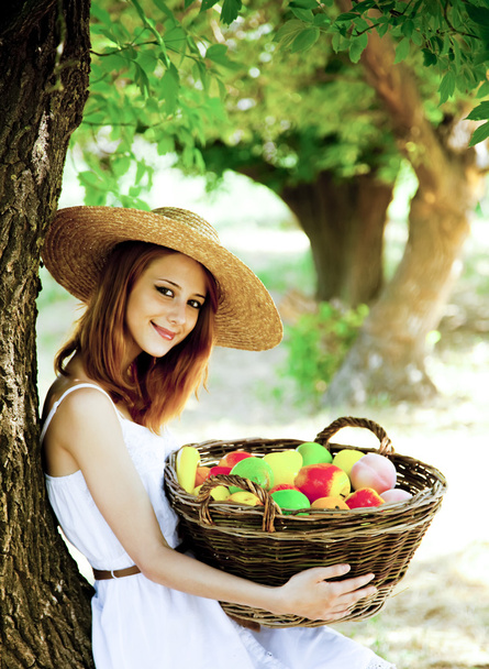 Menina ruiva bonita com frutas na cesta no jardim
. - Foto, Imagem