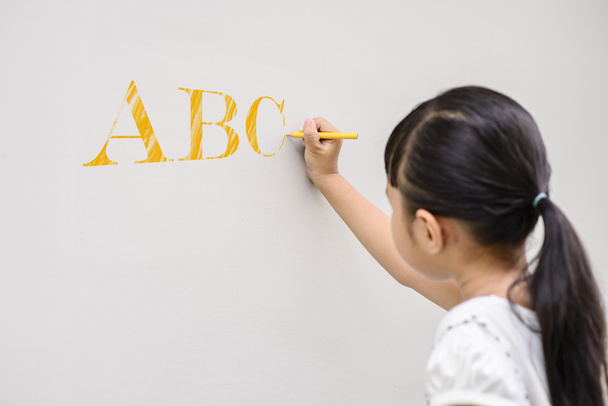Kid writing yellow ABC on the wall - Zdjęcie, obraz