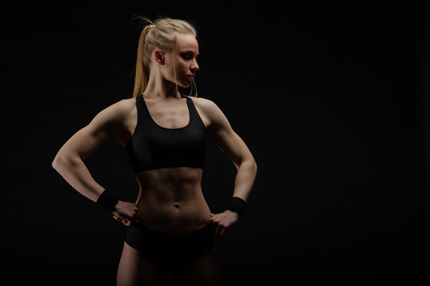 Young muscular woman posing on black - Photo, Image