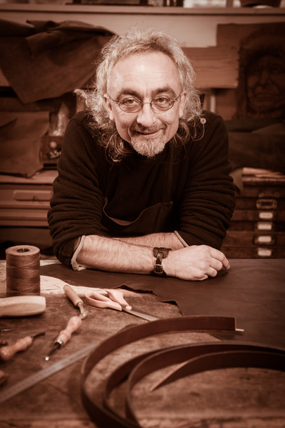 Leather goods craftsman at work in his workshop - Фото, изображение
