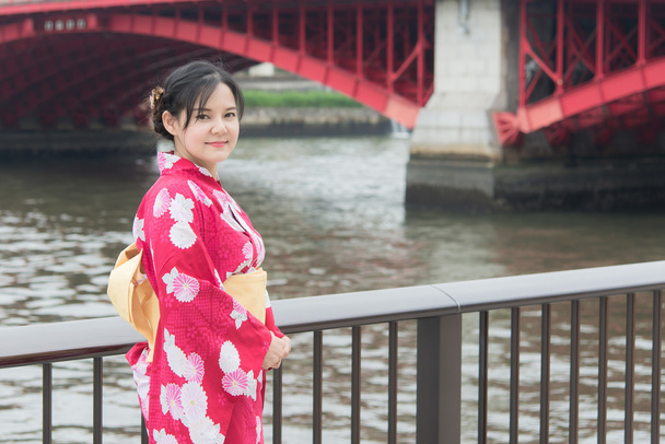 Asian woman wearing red kimono walking on a bridge - Photo, Image