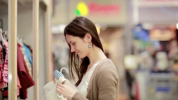 nuori nainen valitsee vaatteita vastasyntyneelle vauvalle
 - Materiaali, video