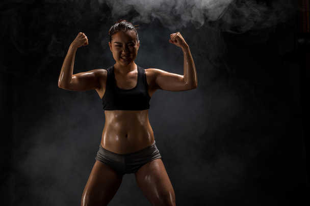 Молодая мускулистая женщина позирует на черном
 - Фото, изображение