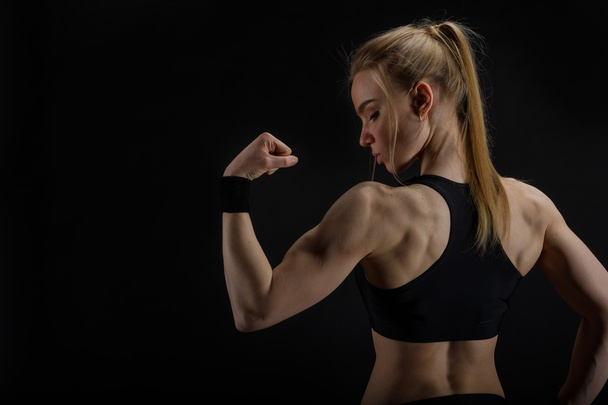junge muskulöse Frau posiert auf schwarz - Foto, Bild