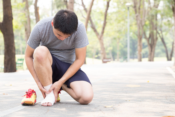 Lesiones deportivas. Hombre con dolor en el tobillo mientras trota
 - Foto, Imagen