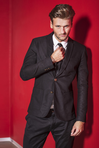 Handsome man in a black suit on a red background - Photo, Image