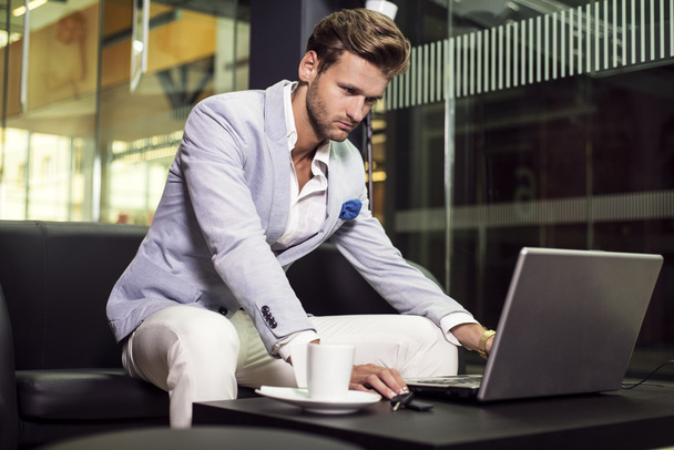 Hombre de negocios guapo sentado en un restaurante con una computadora portátil
 - Foto, imagen