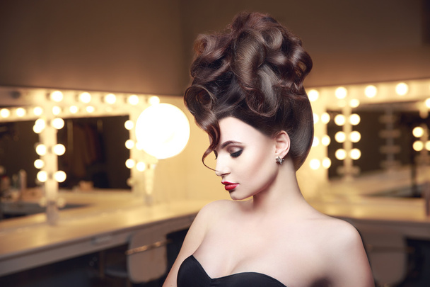 Creative hairstyle of young sexual woman in lingerie. Side view. Red lips. Makeup room with ligts. Updo hair style. - Photo, image