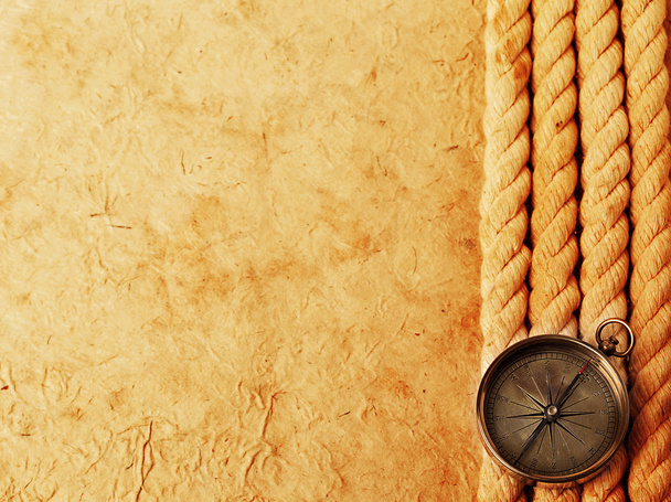 Старовинний латунний компас з мотузкою на старовинному паперовому тлі. Ретро-стенд
. - Фото, зображення