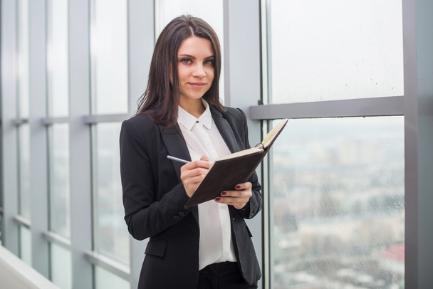 Business woman with notebook is window in office - Фото, зображення