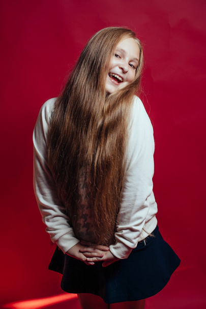 Smiling girl with  blonde hair on red background.studio portrait - Zdjęcie, obraz
