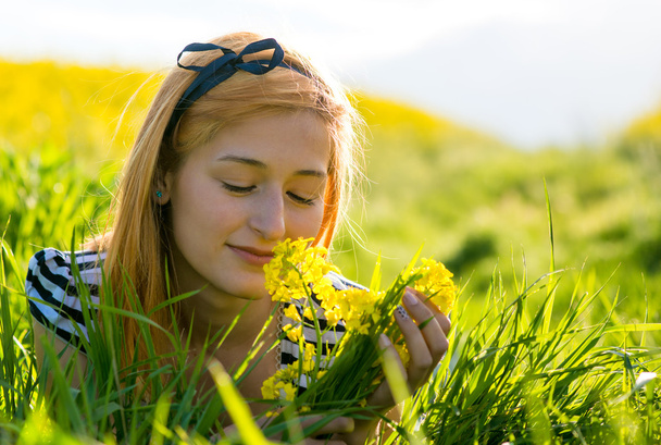portret pięknej młodej kobiety długowłosy leżące w parku i pachnące kwiaty - Zdjęcie, obraz