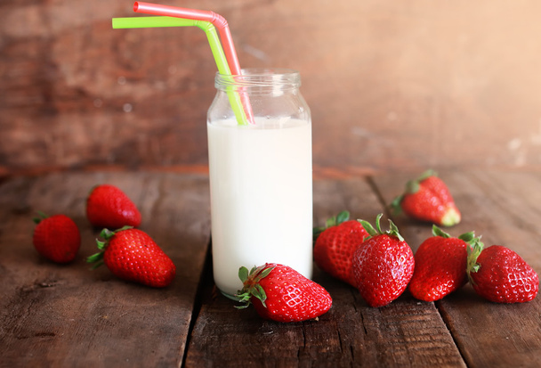 wooden table with strawberries and milk in a glass  - Foto, Imagen
