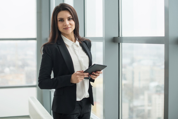 business woman standing at window with tablet - Foto, afbeelding