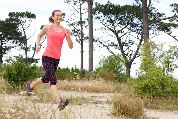 woman smiling while running trail outside - Photo, Image