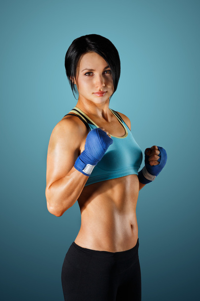 Young sportive woman with dumbbells at blue background - Φωτογραφία, εικόνα