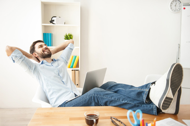 Happy young guy is relaxing at work - Photo, Image