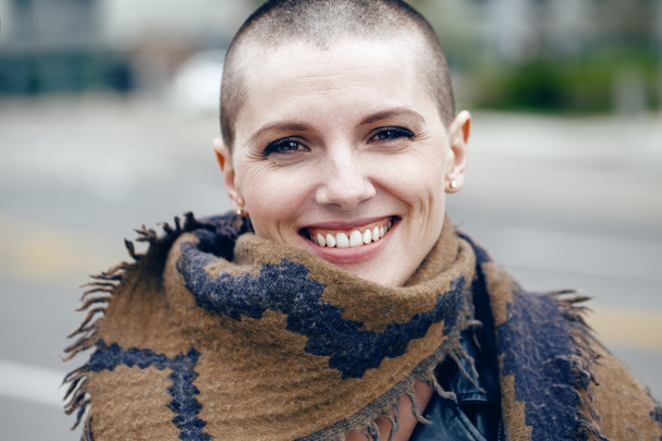 Closeup portrait of happy smiling laughing beautiful Caucasian white young bald girl woman with shaved hair head in leather jacket and scarf shawl looking in camera - Photo, Image