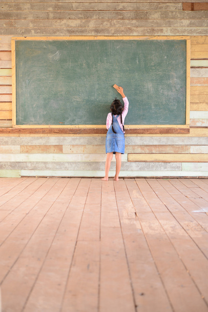 Kid earasing on the old green chalkboard; Wood floor - Zdjęcie, obraz
