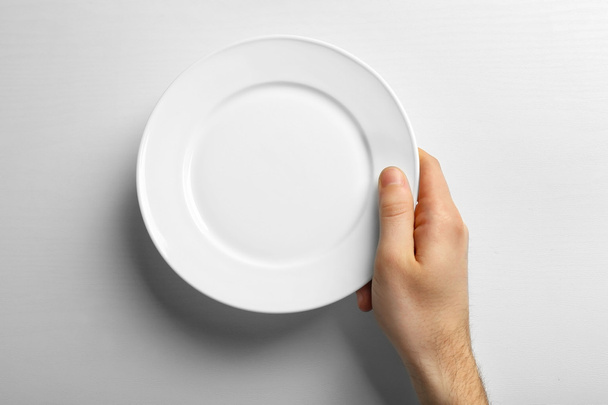 Male hand holding white plate - Фото, зображення