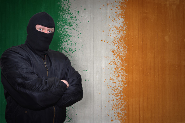 homem perigoso em uma máscara que está perto de uma parede com bandeira nacional pintada de irlanda
 - Foto, Imagem
