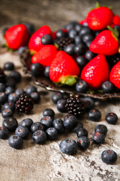 blueberries and strawberries on a plate and stone background - Foto, Imagen