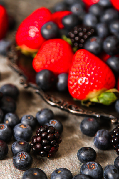 blueberries and strawberries on a plate and stone background - Photo, Image
