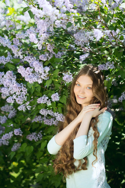 Young beautiful girl in a blossoming spring garden. The blossoming lilac - Foto, Bild