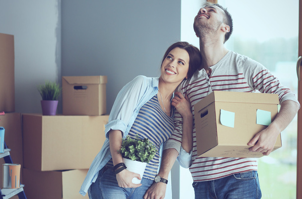 Feliz pareja joven desempacar o empacar cajas y mudarse a un nuevo hogar
 - Foto, Imagen