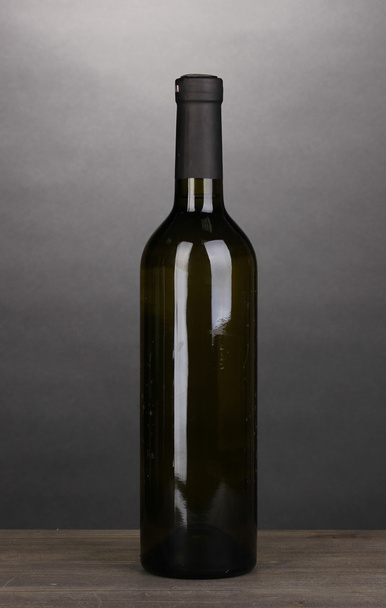 Bottle of great wine on wooden table on grey background - 写真・画像
