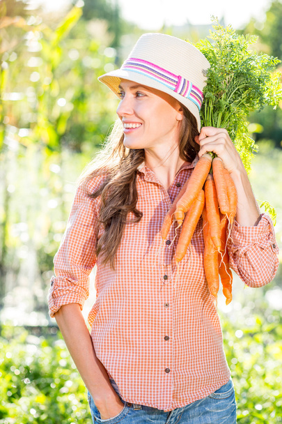 Gardening - Woman with organic carrots in a vegetable garden - Fotoğraf, Görsel