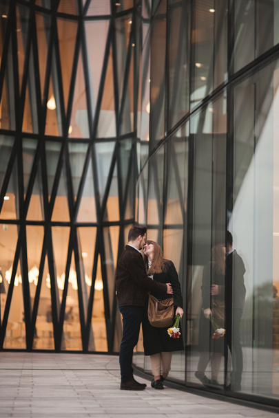 Stylish loving couple kissing and hugging near modern building - Фото, изображение