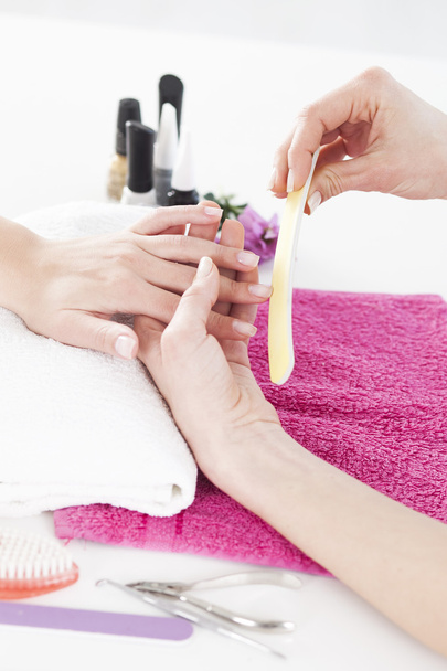 Woman in a nail salon receiving a manicure by a beautician.  - Fotó, kép