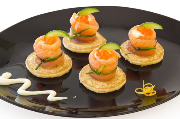 Rotoli di salmone rosso con formaggio, caviale e cetriolo su "blinis"
 - Foto, immagini