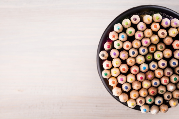 Цветные карандаши в офисной корзине на деревянном фоне
 - Фото, изображение