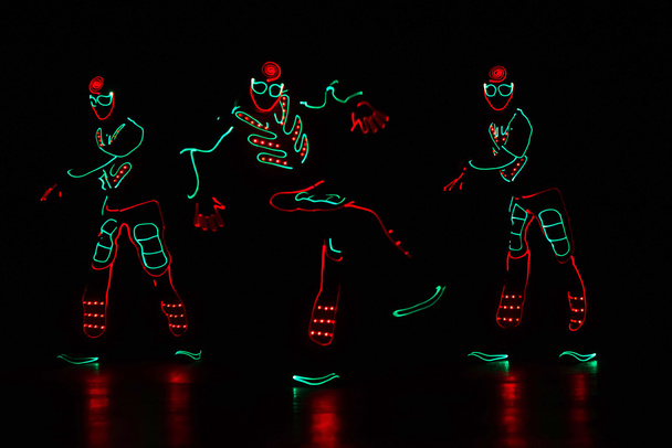 ballerini in abiti a led su sfondo scuro, spettacolo a colori
  - Foto, immagini