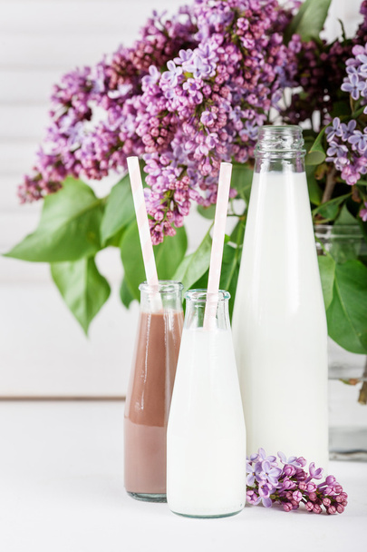 Солодкі шоколадні молочні коктейлі та красиві бузкові квіти у вазі
 - Фото, зображення