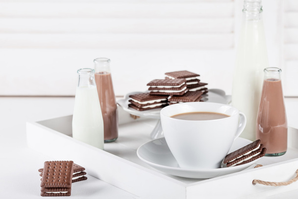 Filiżanka kawy na białej tacy z herbatnikami i mlekami czekoladowym - Zdjęcie, obraz