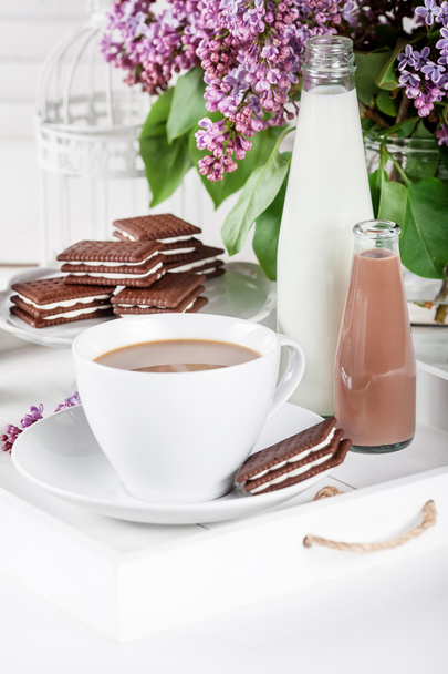 Kopje koffie en enkele flessen melk op een wit dienblad met lila - Foto, afbeelding