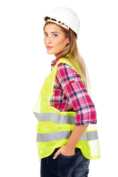 Smiling female builder holding hands in pocket - Foto, imagen