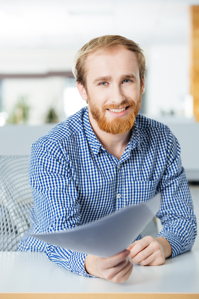 Cheerful businessman sitting in office and giving papers to you  - Photo, image