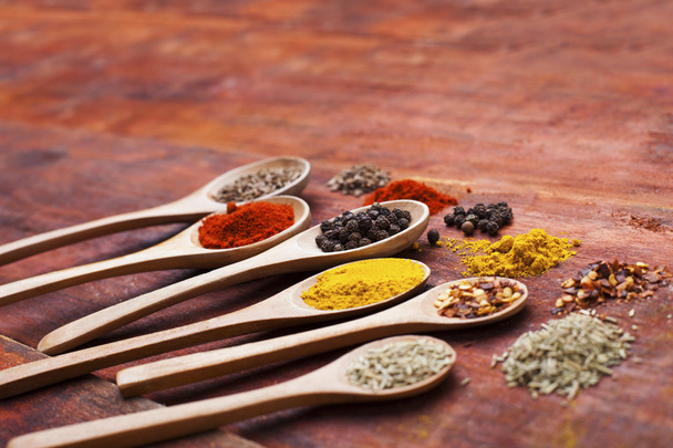 Wooden spoons full of aromatic herbs and spices on a wooden cutting board - Photo, Image