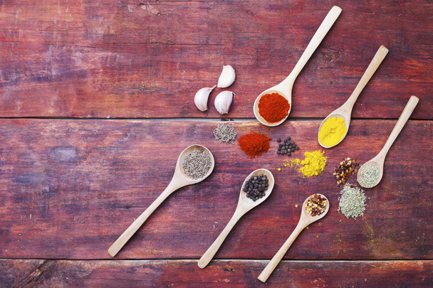 Wooden spoons full of aromatic herbs and spices on a wooden cutting board - Photo, Image