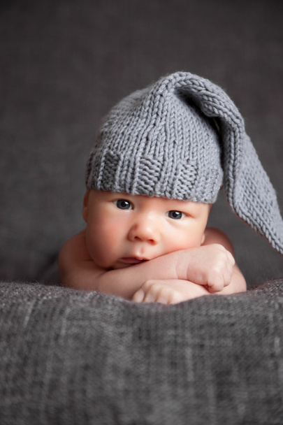 Όμορφη νεογέννητο φορώντας ένα χαριτωμένο γκρι καπέλο - Φωτογραφία, εικόνα