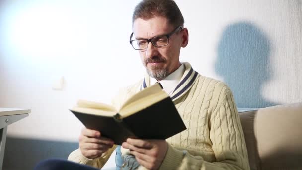 dorosły człowiek z brodą ubrany w okulary czytanie książki - Materiał filmowy, wideo