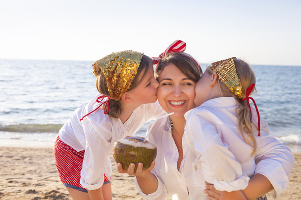 Happy mother with her adorable daughters drinking coconut milk  - Photo, Image