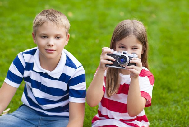 Όμορφο μικρό αδελφό και αδελφή παίζει με μια φωτογραφική μηχανή για το καλοκαίρι - Φωτογραφία, εικόνα