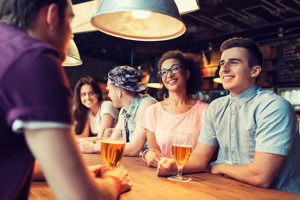 happy friends drinking beer and talking at bar - Φωτογραφία, εικόνα